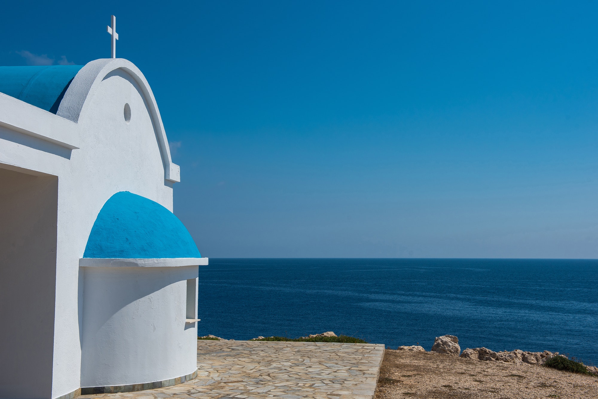 Whitewashed church with blue roof near the sea. Agioi Anargyroi chapel, Cyprus